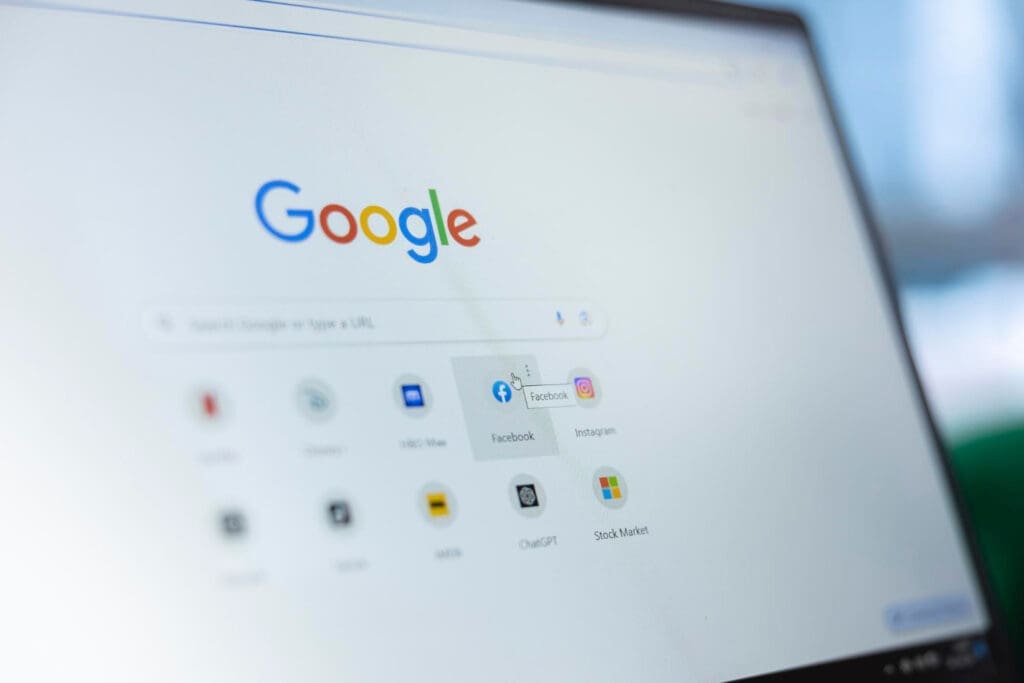 A computer screen displays the Google homepage with the search bar and shortcuts to popular websites like Facebook, YouTube, Instagram, and WhatsApp. The mouse cursor hovers over the Facebook icon.